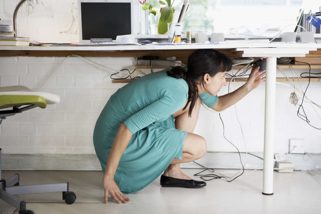 Woman Adjusting Cables Under Desk